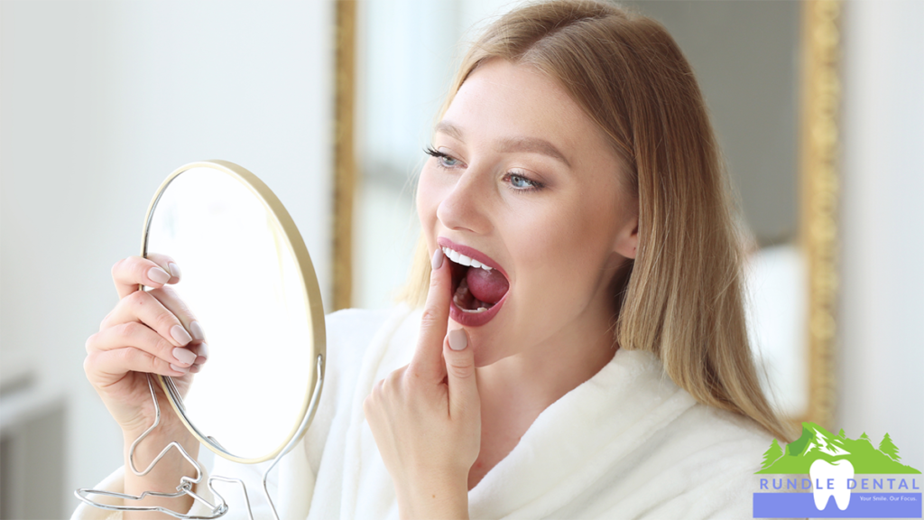 A woman examining her teeth in the mirror.