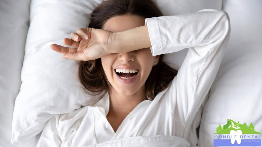 A woman laughing in bed.