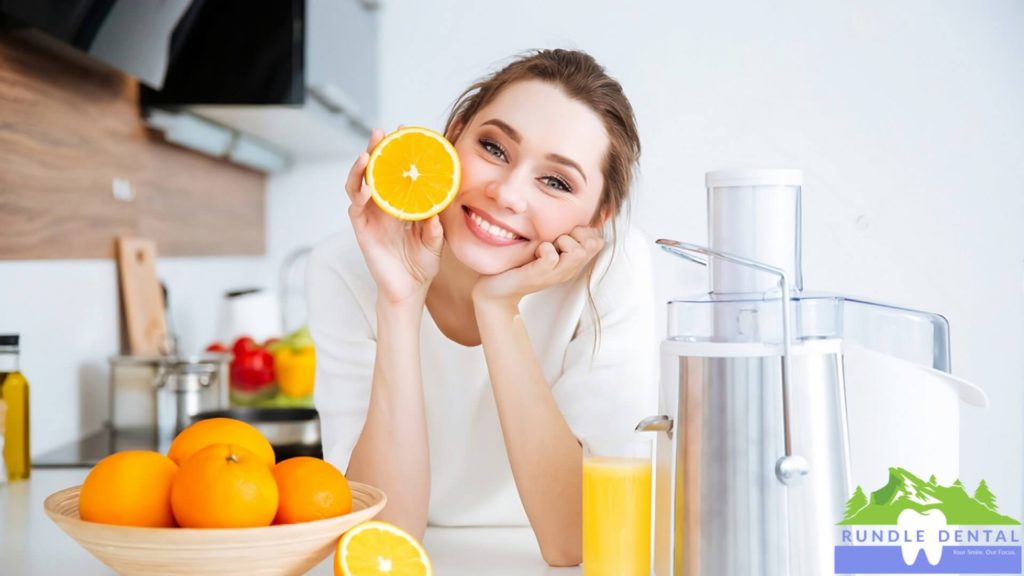 A woman smiling and holding up an orange.